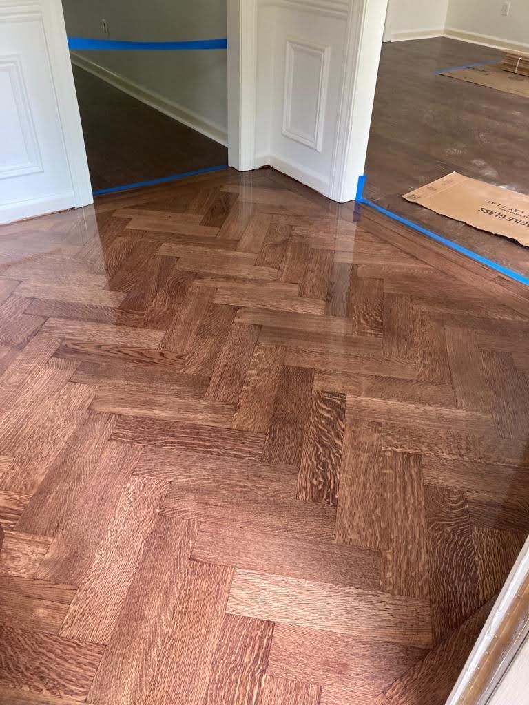 A wooden floor with a herringbone pattern in a room.