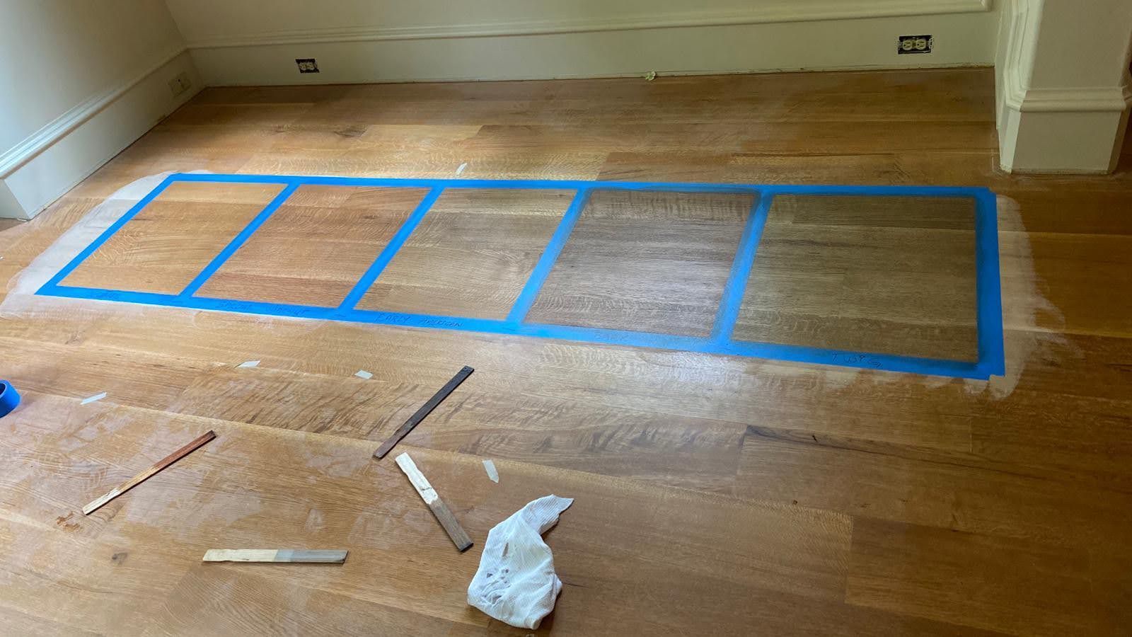 A wooden floor with blue tape and a ruler on it.