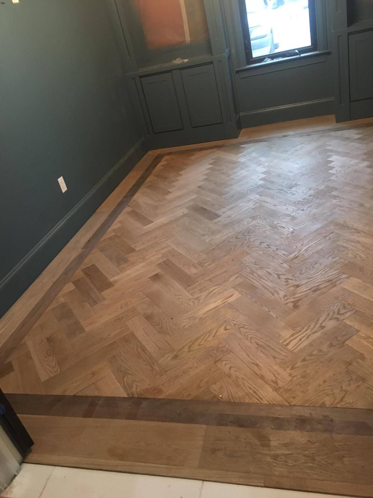 A wooden floor with a herringbone pattern in a room.