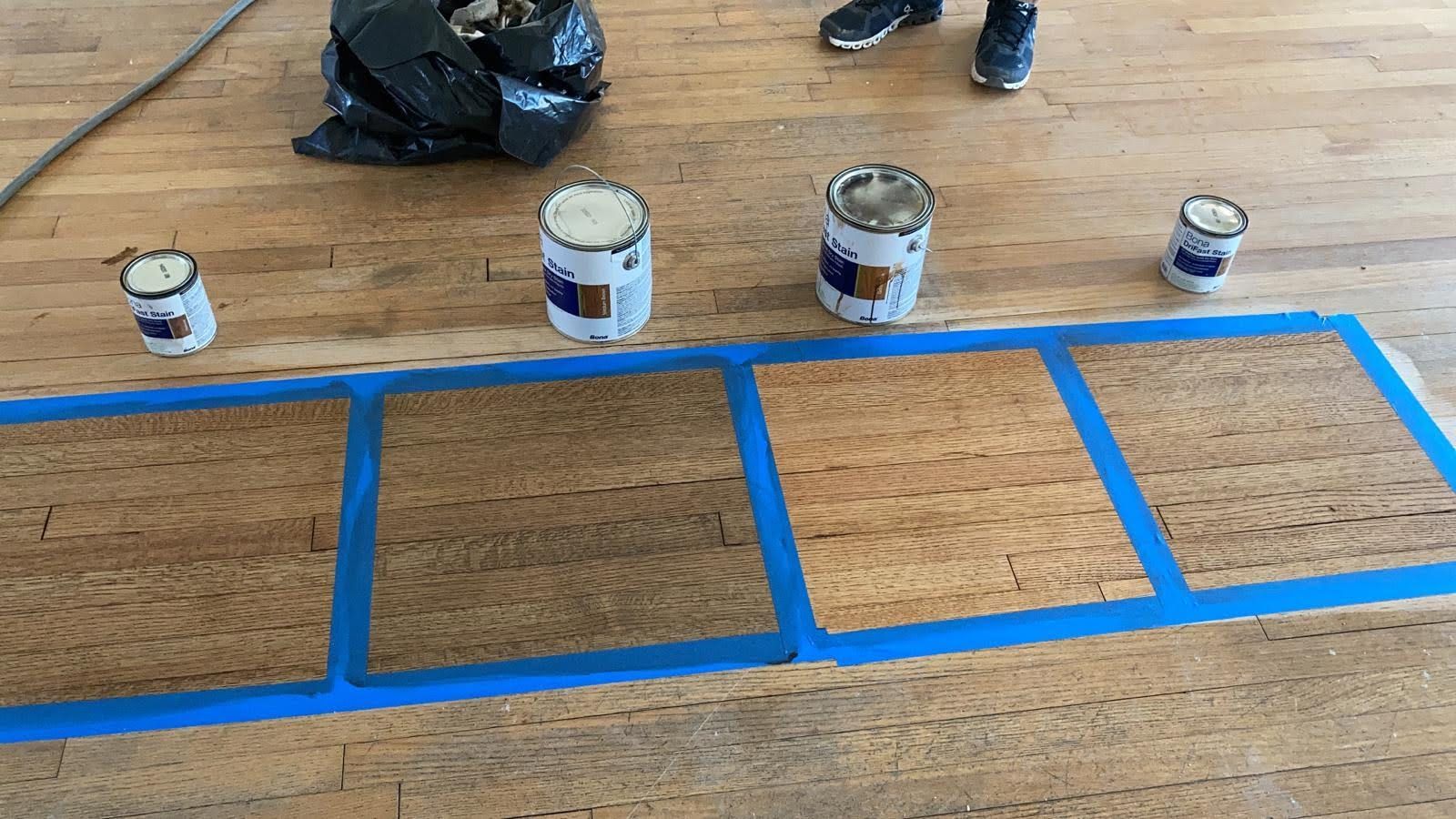 Four cans of paint are sitting on a wooden floor.