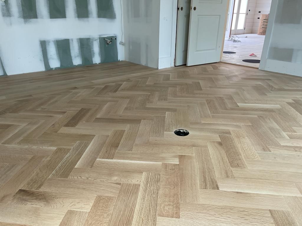 A wooden floor with a herringbone pattern in a room.