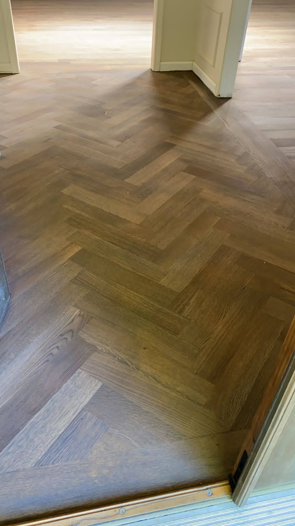 A close up of a wooden floor with a herringbone pattern in a room.