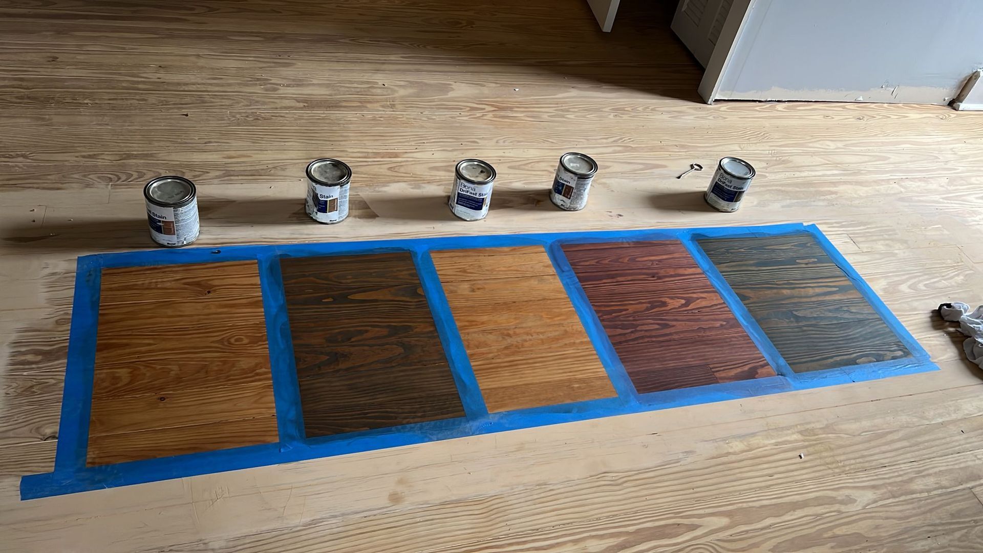 A bunch of cans of paint are sitting on a wooden floor.