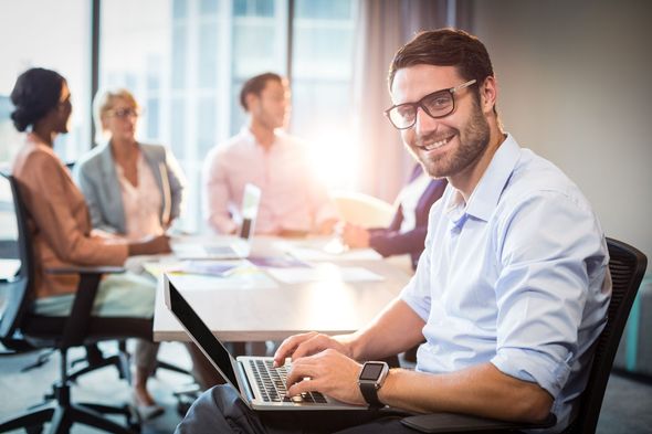 Man using laptop while coworker interacting