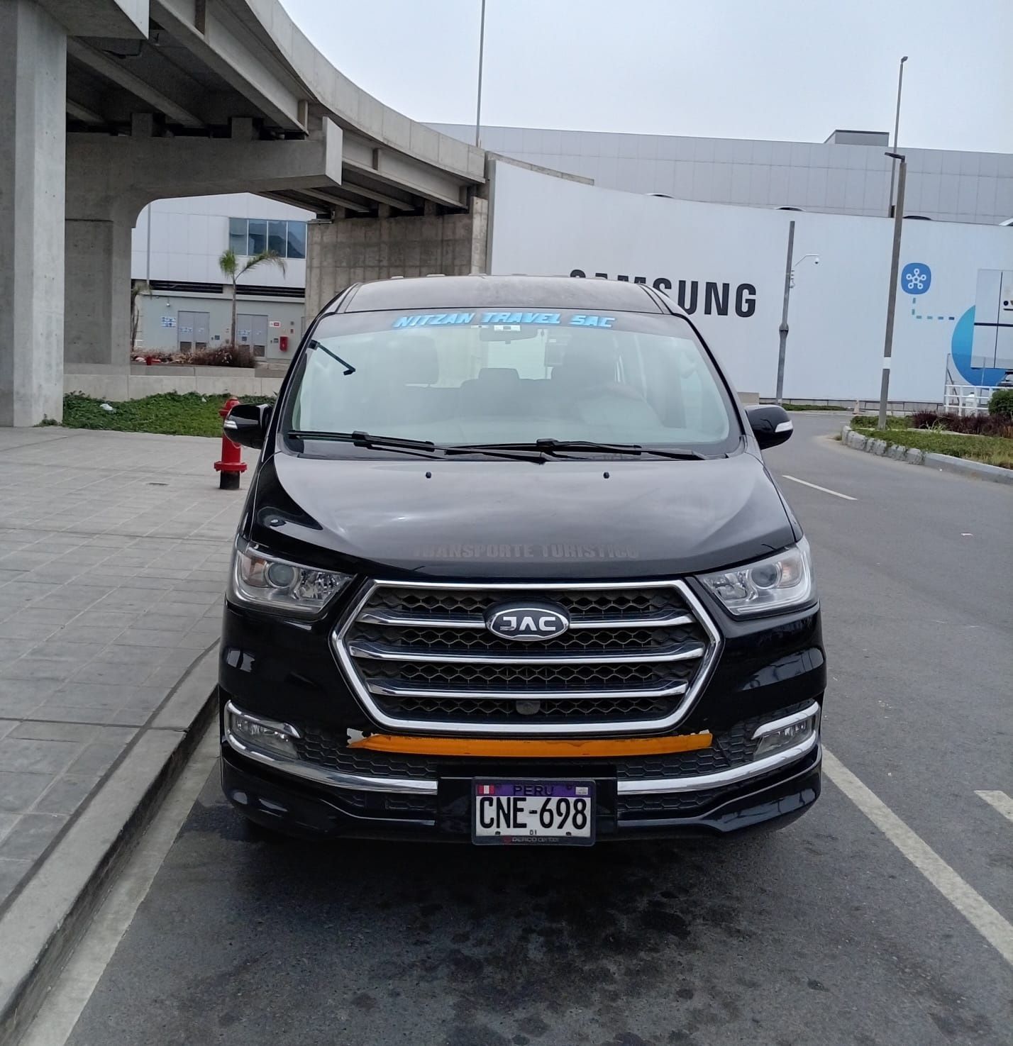 SUV negro estacionado junto a la acera debajo de un paso elevado en una calle de la ciudad.