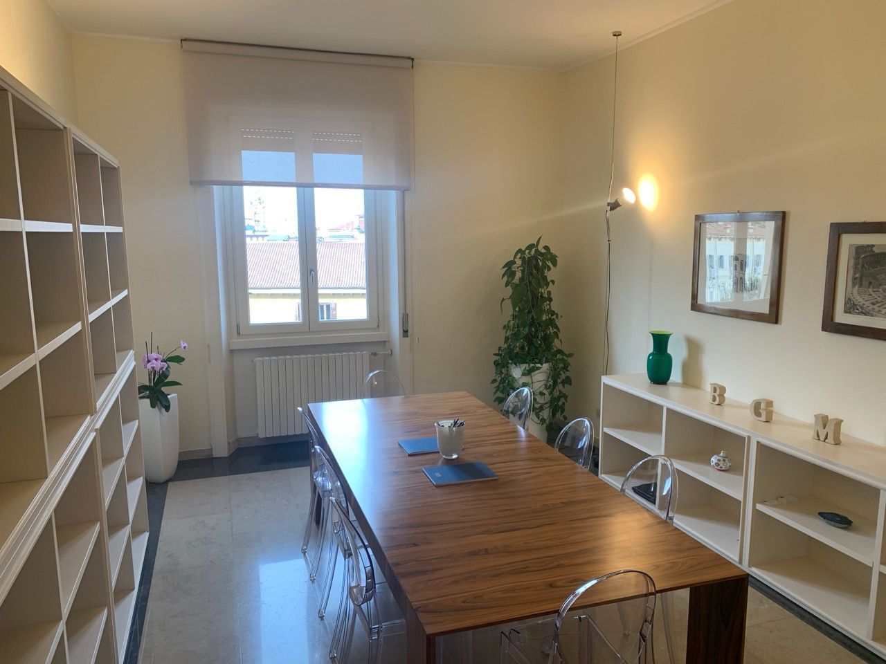 Una stanza con un lungo tavolo di legno e sedie trasparenti