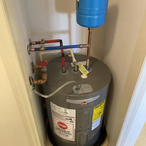 A water heater is sitting in a closet next to a wall | The Duke Of Plumbing