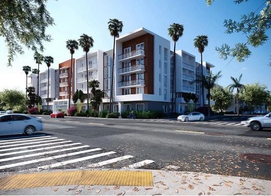 Modern apartment building at a street corner with palm trees and cars passing by