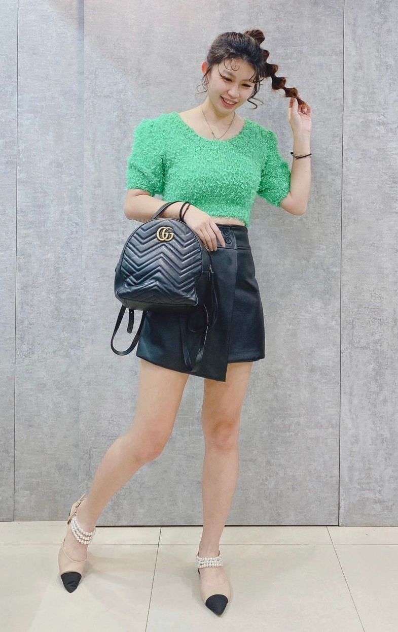 一名身穿綠色露臍上衣和黑色短褲的女士背著黑色背包。