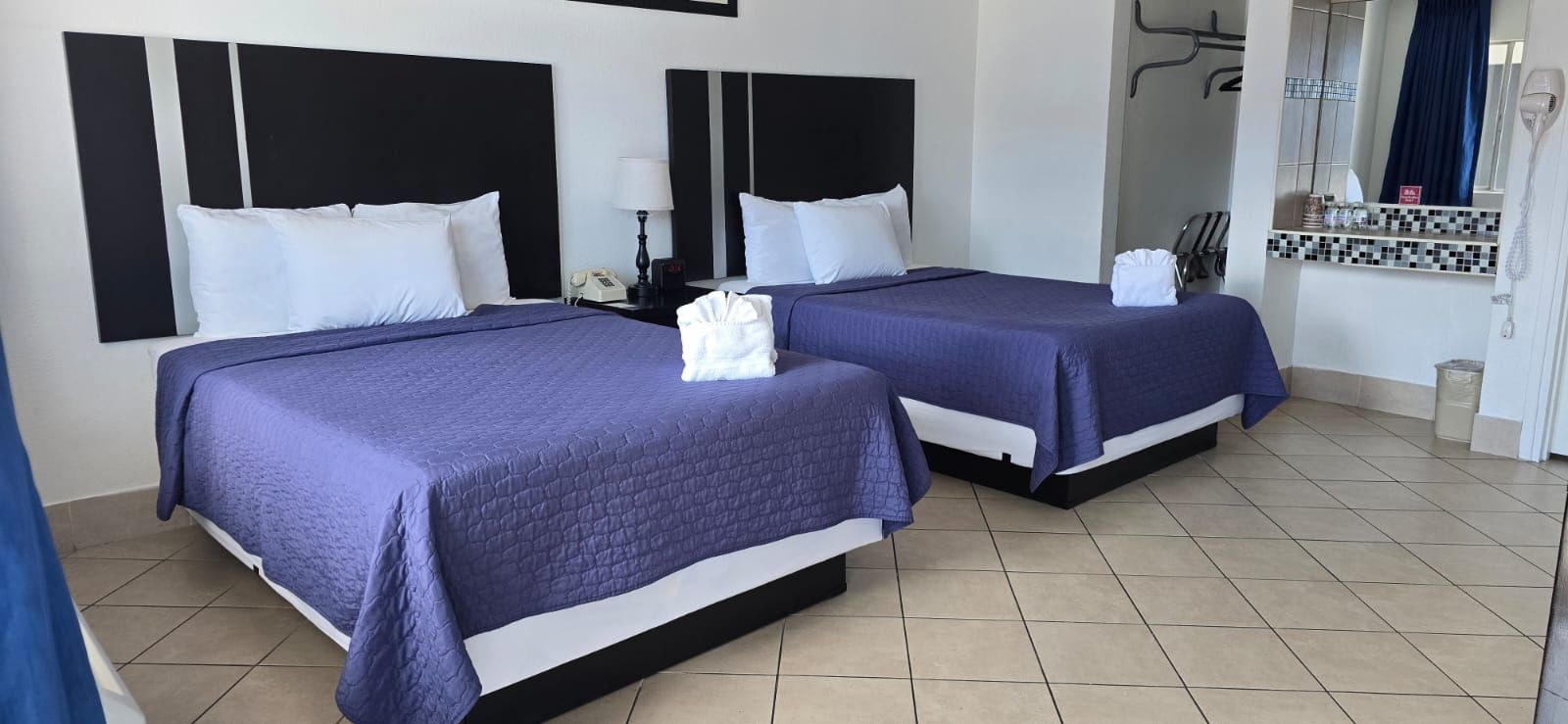 A hotel room with two beds and a sink.