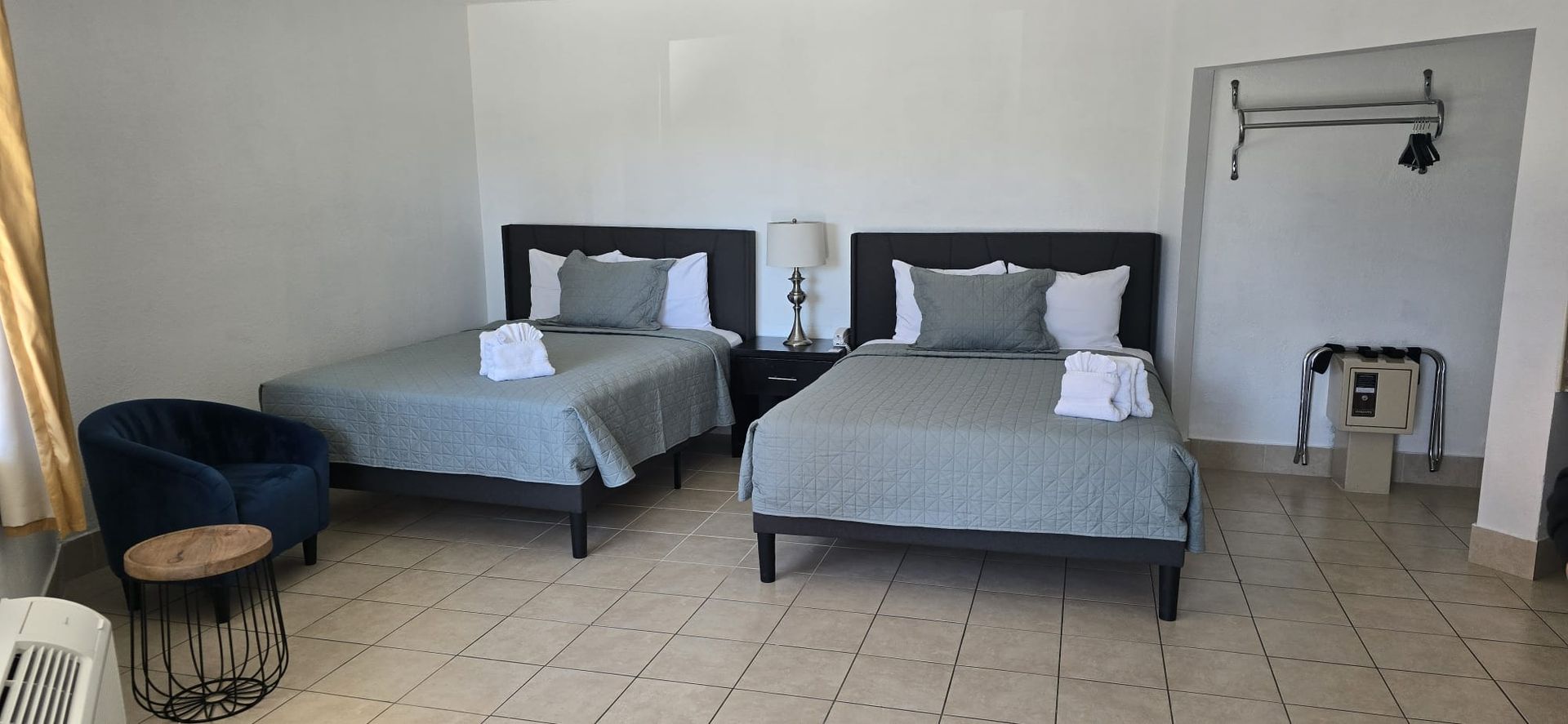 A hotel room with two beds , a chair and a table.