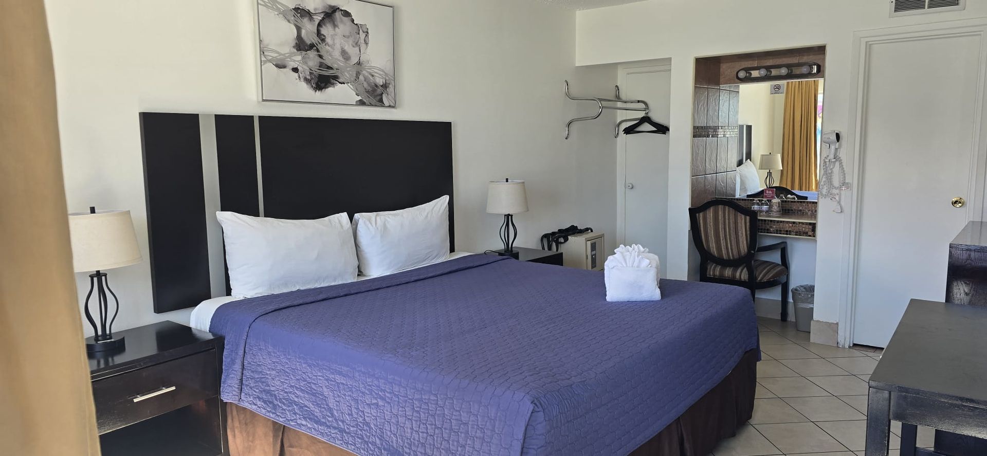 A hotel room with a king size bed and a purple blanket.