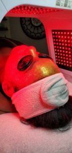 A woman is getting a red light treatment on her face.