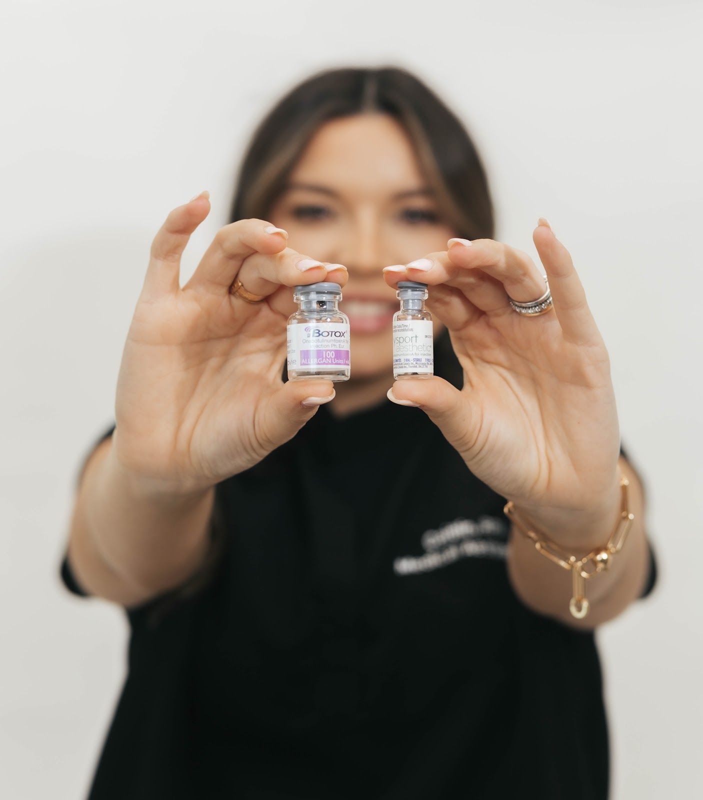 Woman holding two small vials, focused on the vials.