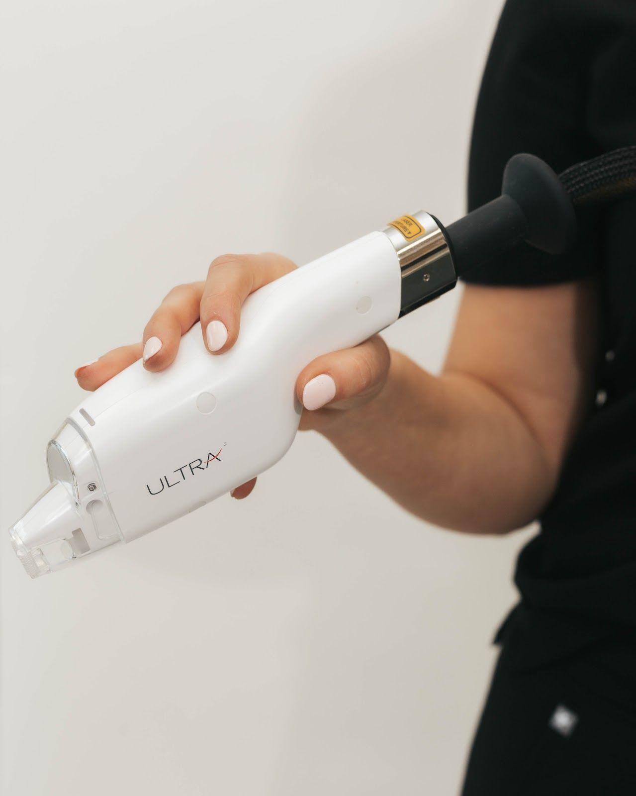 Woman's hand holding a white and silver UltraMax device, connected to a black tube.