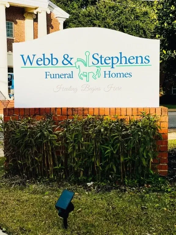 Webb & Stephens Funeral Homes sign in front of brick building and greenery