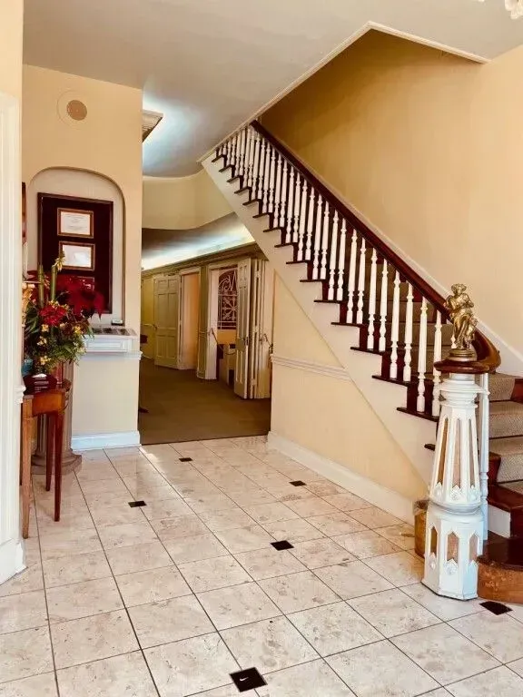Interior foyer with tiled floor, staircase, and hallway in a beige home