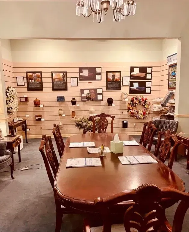 Elegant dining room with polished wood table, chairs, chandelier, and wall art displays.