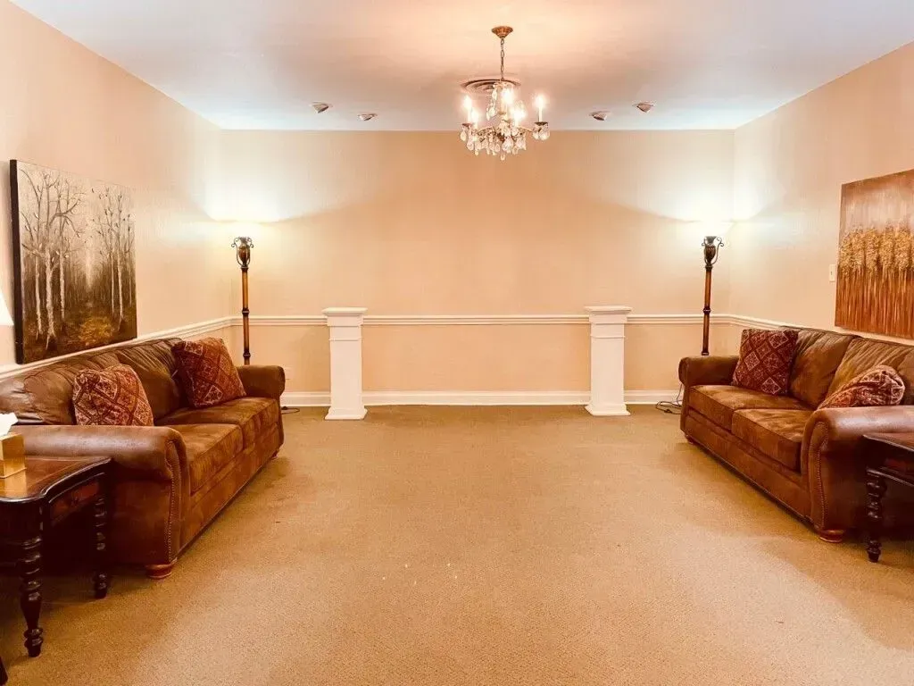 Elegant living room with two brown sofas, beige carpet, wall sconces, and a chandelier