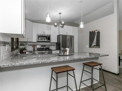 A kitchen with granite counter tops and stools