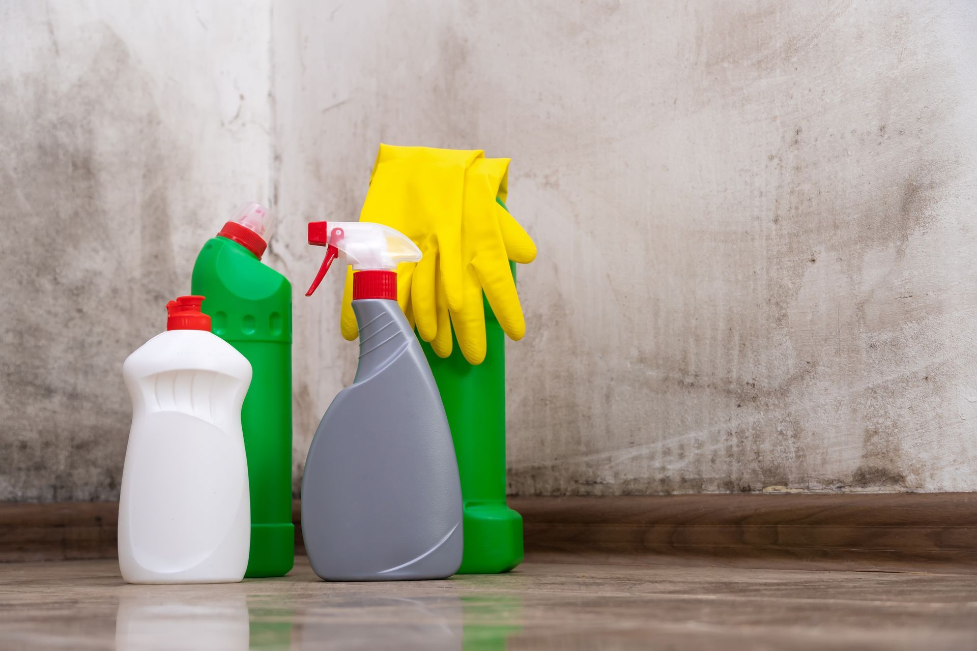 A bunch of cleaning supplies are sitting on the floor in front of a wall.