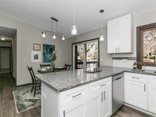 A kitchen with granite counter tops , white cabinets , stainless steel appliances and a large island.