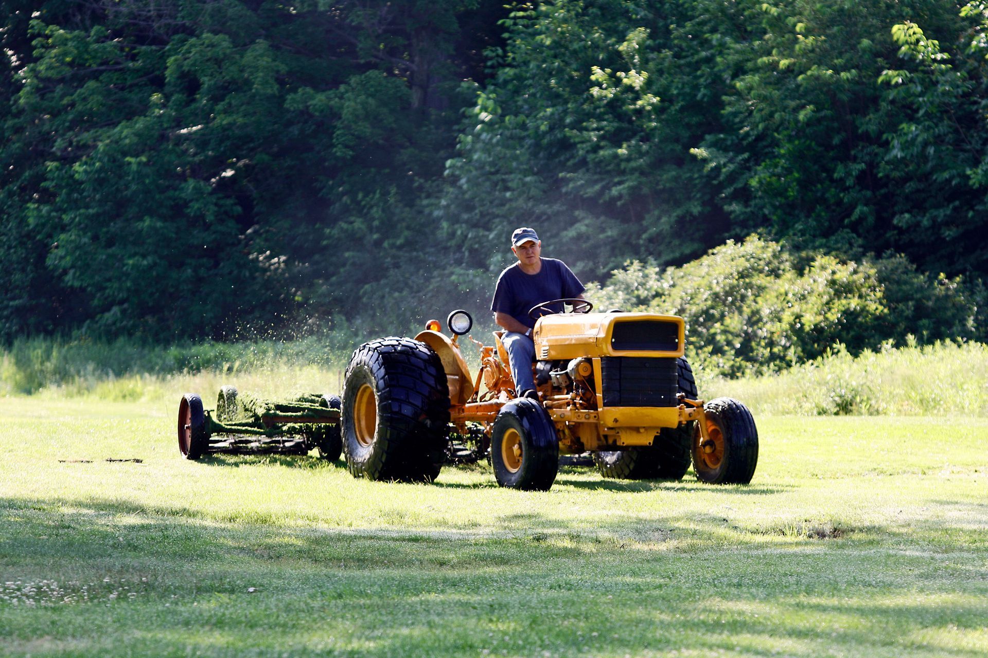 A man is riding a yellow tractor in a field