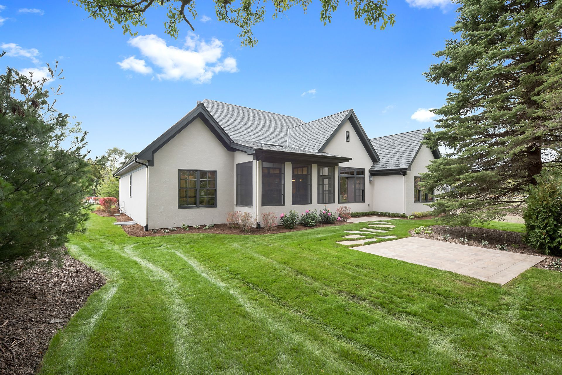 A white house with a gray roof is sitting on top of a lush green lawn.