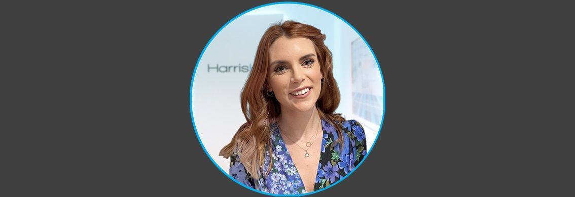 Woman with auburn hair smiles, wearing a patterned top in a blue circle on a gray background.