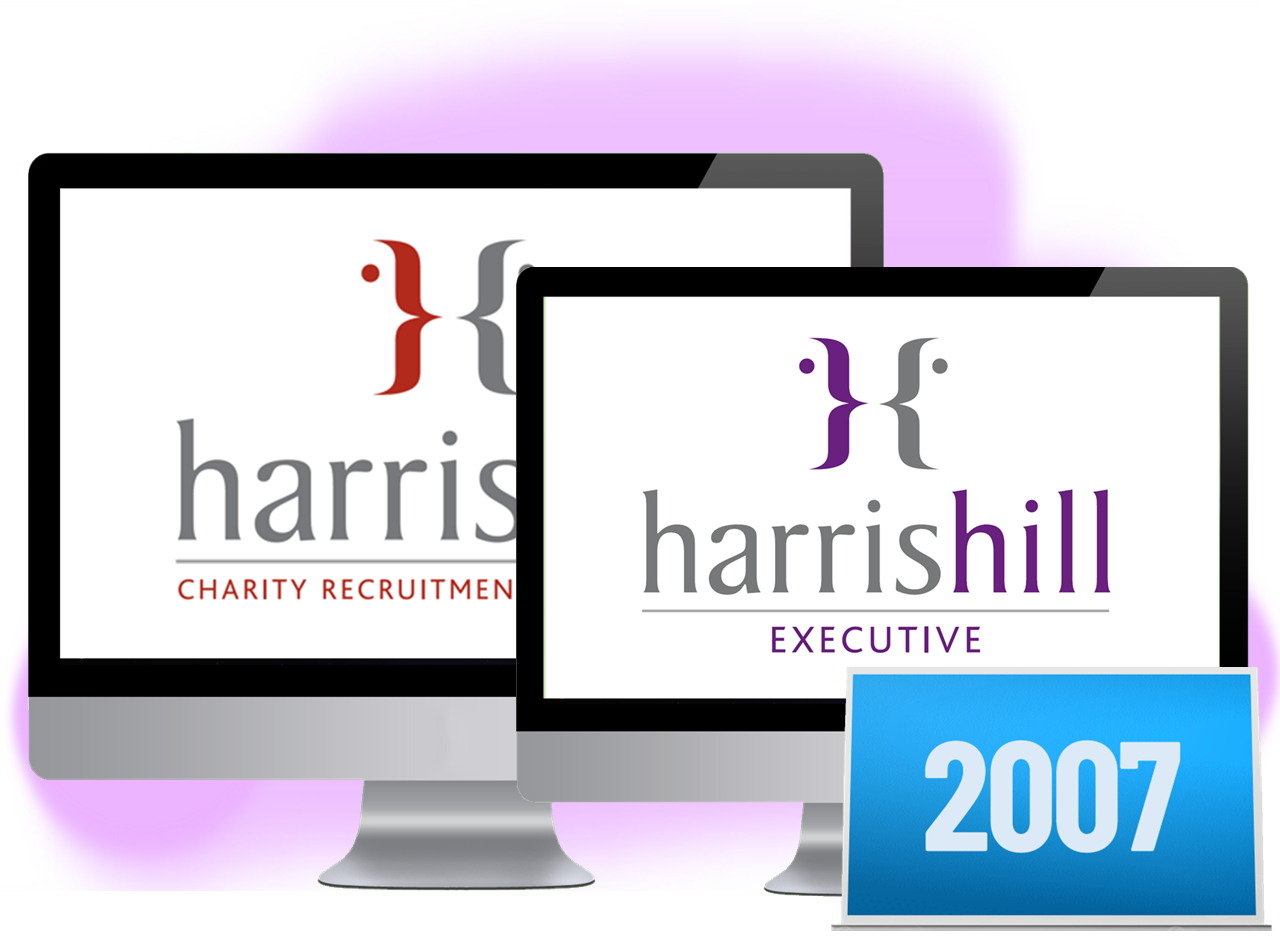 Two computer monitors display the Harris Hill logo, one with 
