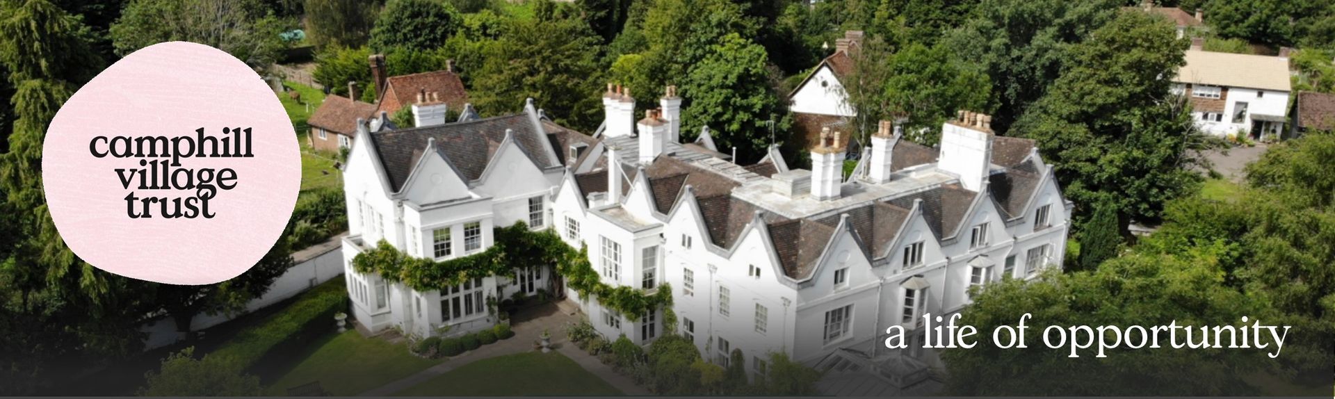 Aerial view of white building in trees with pink circle logo 