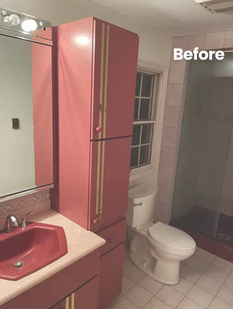 Pink bathroom with tall cabinet, sink, toilet, and shower before renovation.