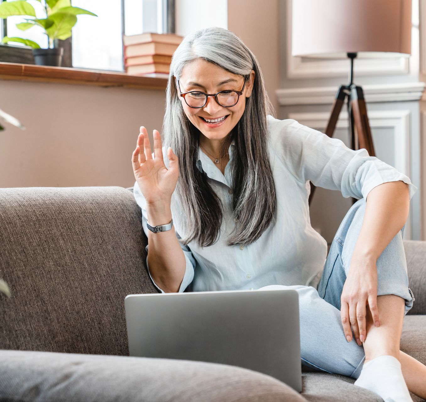 A woman is sitting on a couch using a laptop computer.