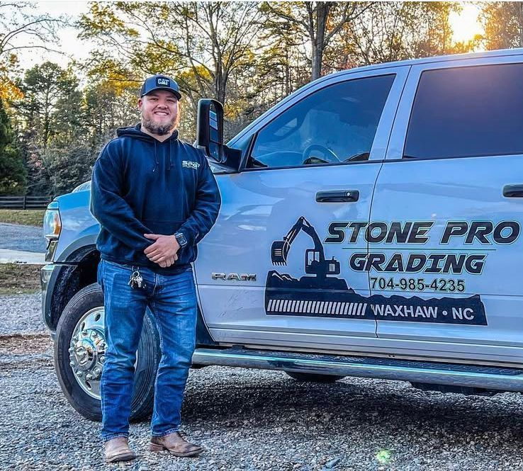 A man is standing in front of a truck that says stone pro grading.