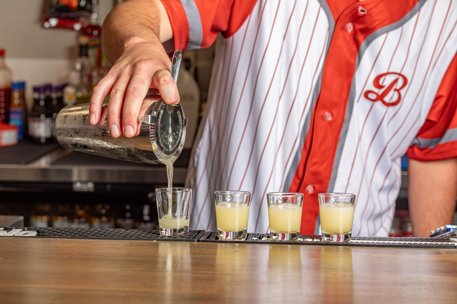 A bartender is pouring a drink into a shot glass.