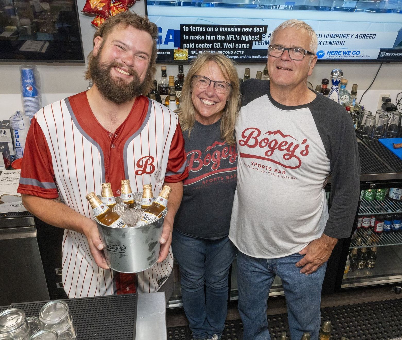 A man in a bogey 's shirt is holding a bucket of beer