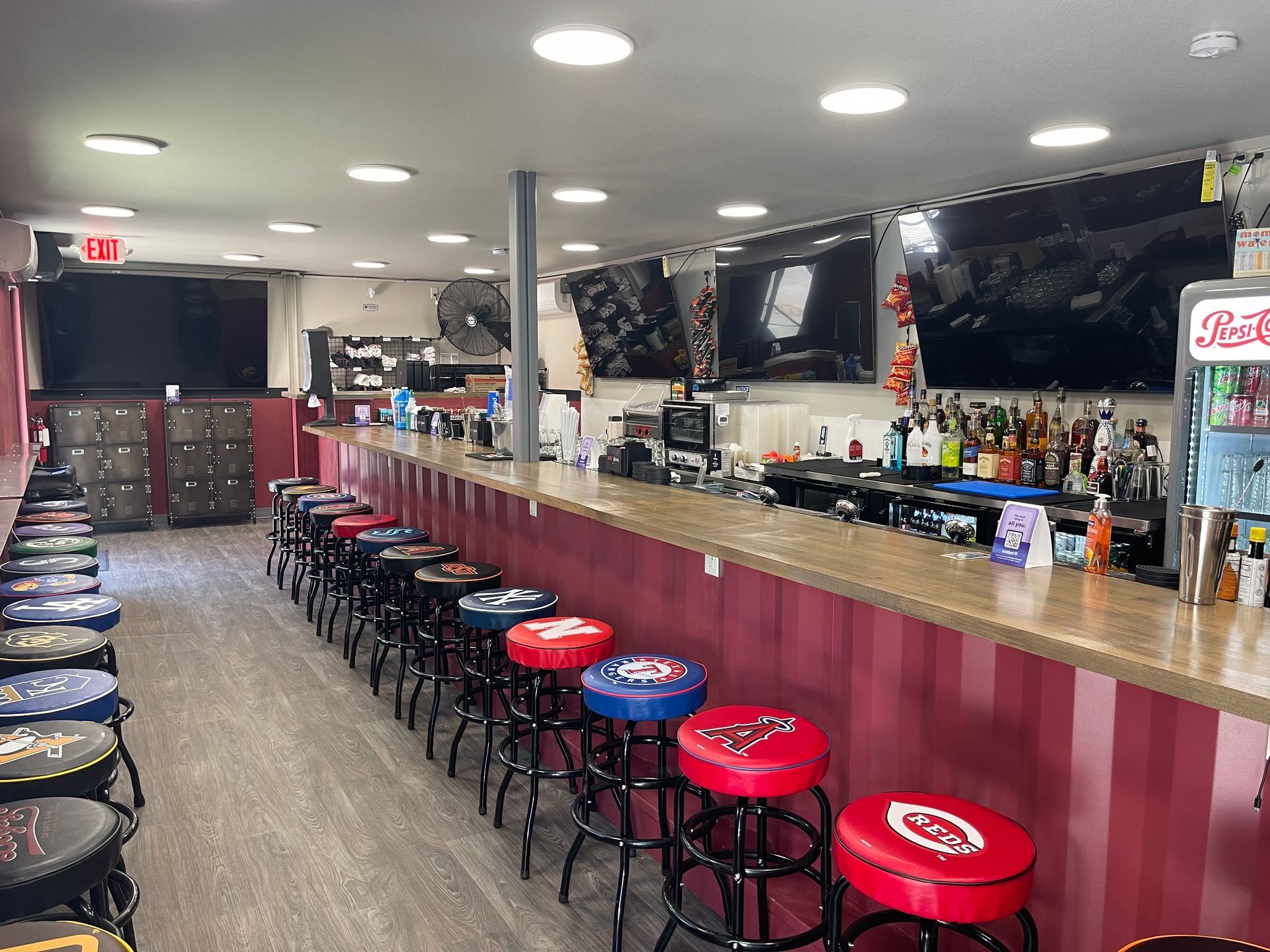 A long bar with a lot of stools and a pepsi machine.