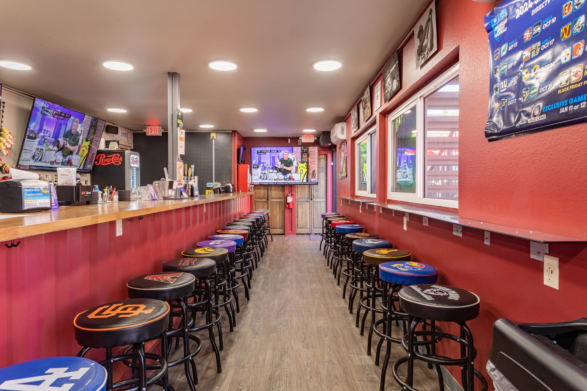 A long bar with a lot of stools and a television on the wall.