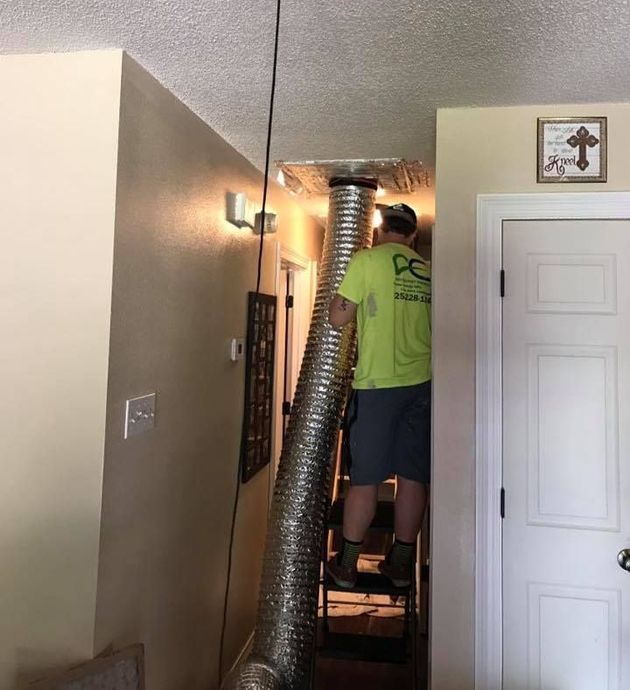 A man is standing in a hallway with a hose hanging from the ceiling.