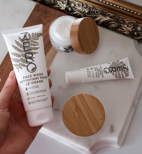 A person is holding a tube of organic face wash