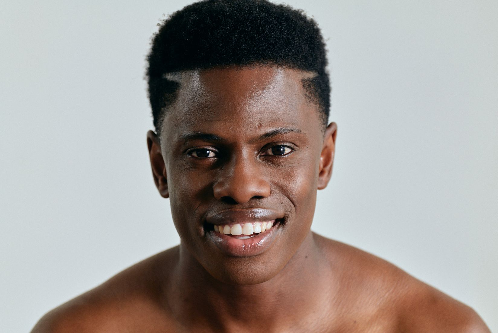 A shirtless man is smiling and looking at the camera.