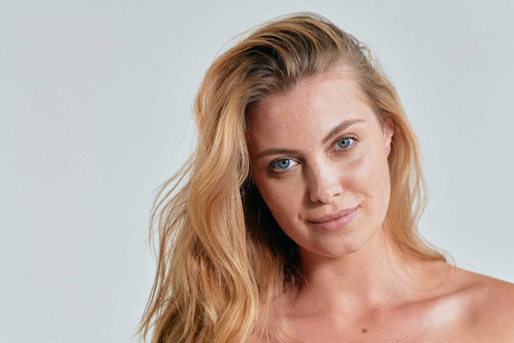 A woman with long blonde hair is smiling and looking at the camera.