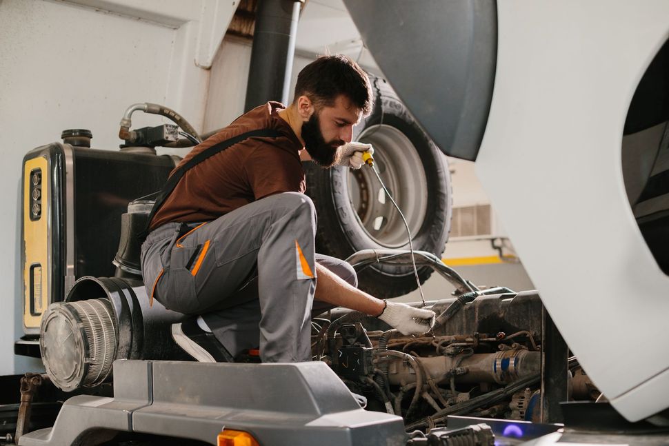 Mechanic crouching beside an airplane engine during maintenance, with a wheel visible in the background