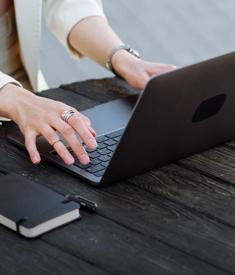 A woman with a ring on her finger is typing on a laptop.