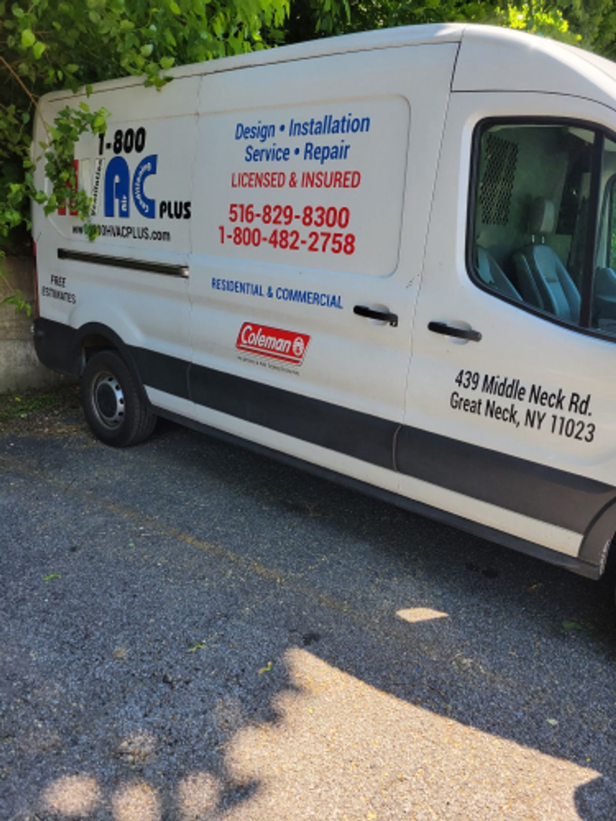 White AC Plus service van parked on asphalt; business contact information on side.