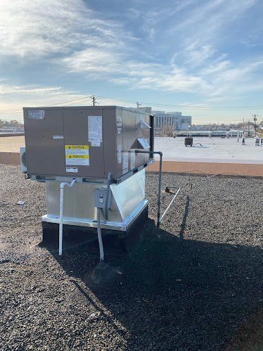 HVAC unit on a rooftop, with a clear sky and buildings in the background.