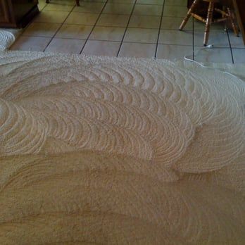 A white rug is sitting on a tiled floor in a room.