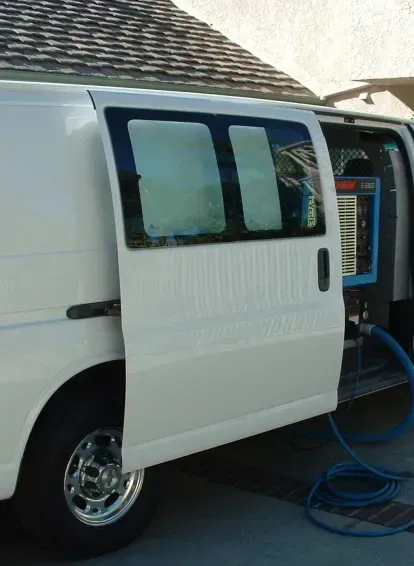 A white van with its doors open and a hose attached to it