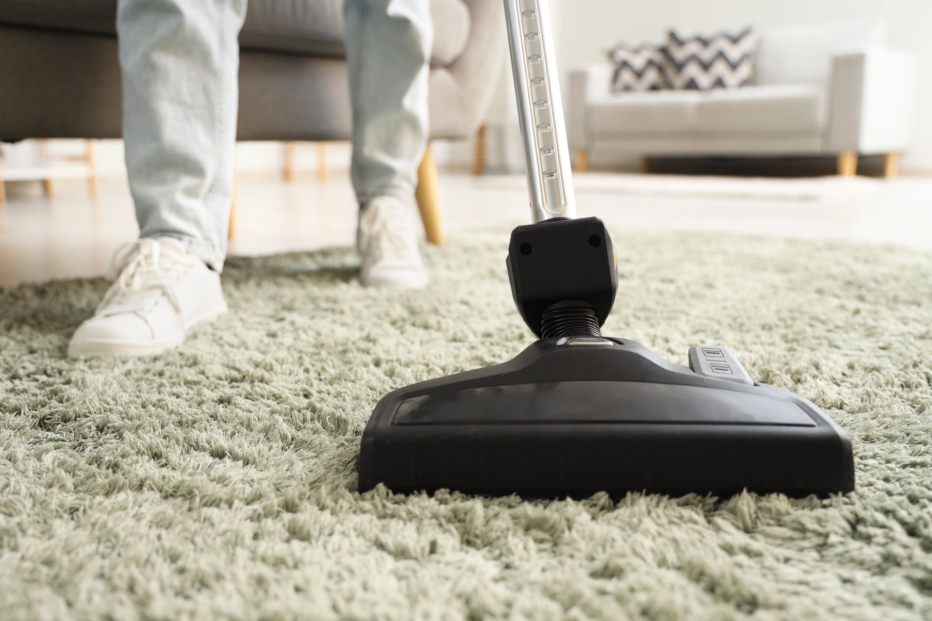 A person is vacuuming a carpet in a living room.