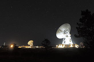 Photo showing deep space antennas illuminated at night